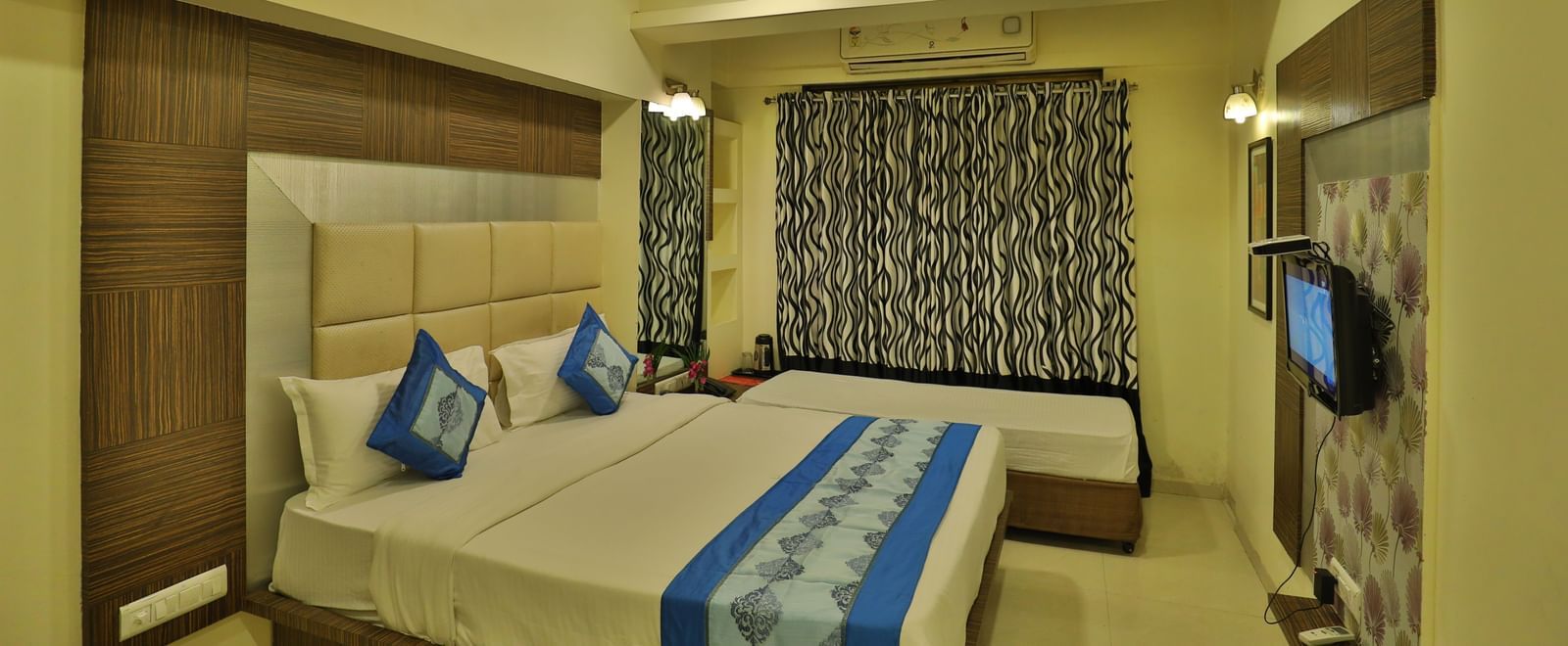 A cosy hotel room with a large bed, side tables, a television, and ample natural light - Retreat Heritage, Lonavala