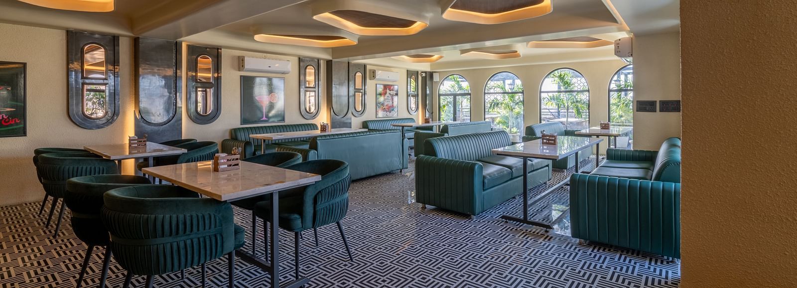 Indoor restaurant with green lounge chairs, framed wall art, and soft ceiling lighting at Hotel Highway King, Jaipur.