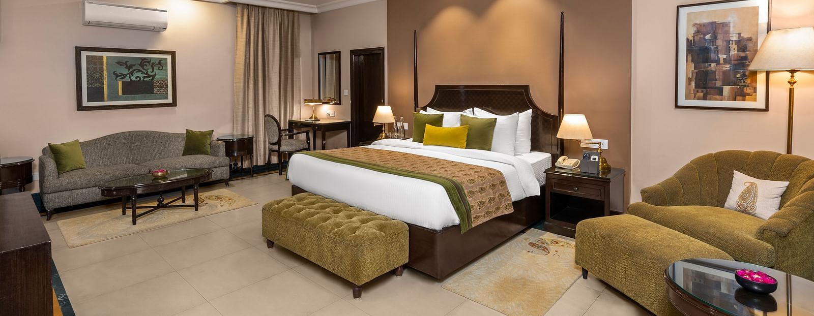 Ganga View Suite with two sofas and a large bed in the middle with green covers - Ganga Lahari, Haridwar