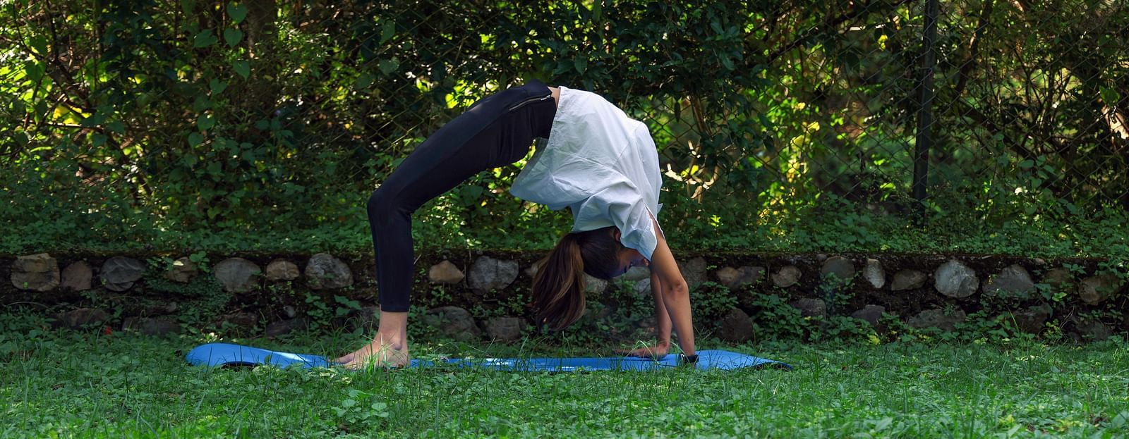 A woman practicing yoga surrounded by lush greenery at The Sylvan Retreat, Dehradun. 