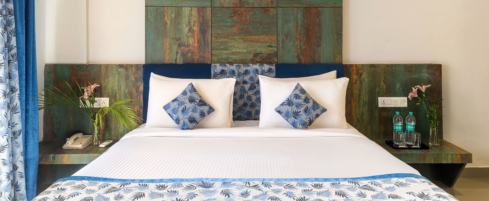 A bedroom with a made bed, decorative pillows, and artwork on the wall - Via Lakhela Resort & Spa