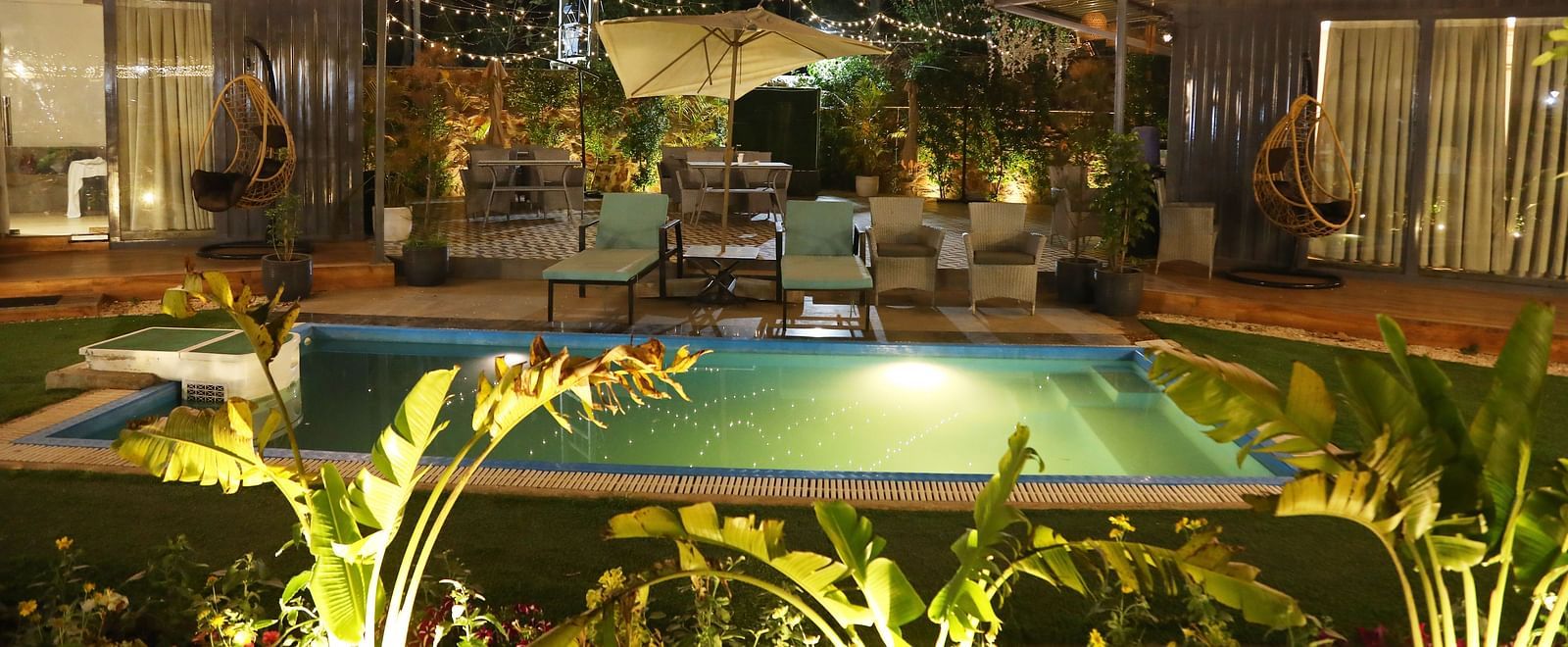 Night view of swimming pool with plants and lighting around the villa at Tisya Farms, Gurgaon.