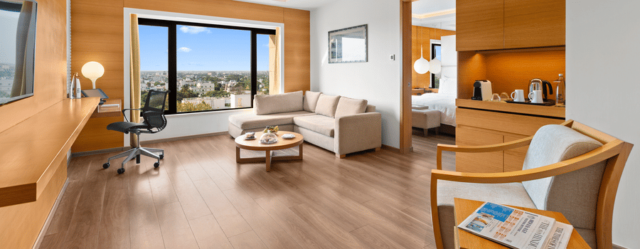 Side view of the Club Suite living room with a cozy sofa in the corner and a view from the window at The Residency Towers Coimbatore