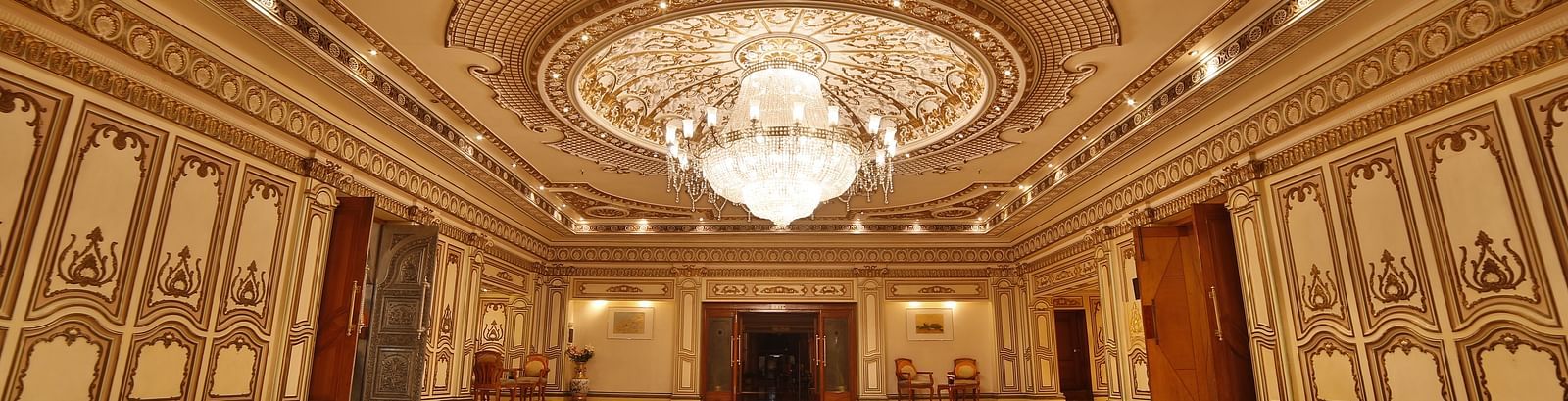  Interiors of Rang Mahal hall A grand hotel suite with an opulent red and white decor, large bed, and seating area, reflecting a traditional style at Sitara Luxury Hotel in Hyderabad near Ramoji Film City.
