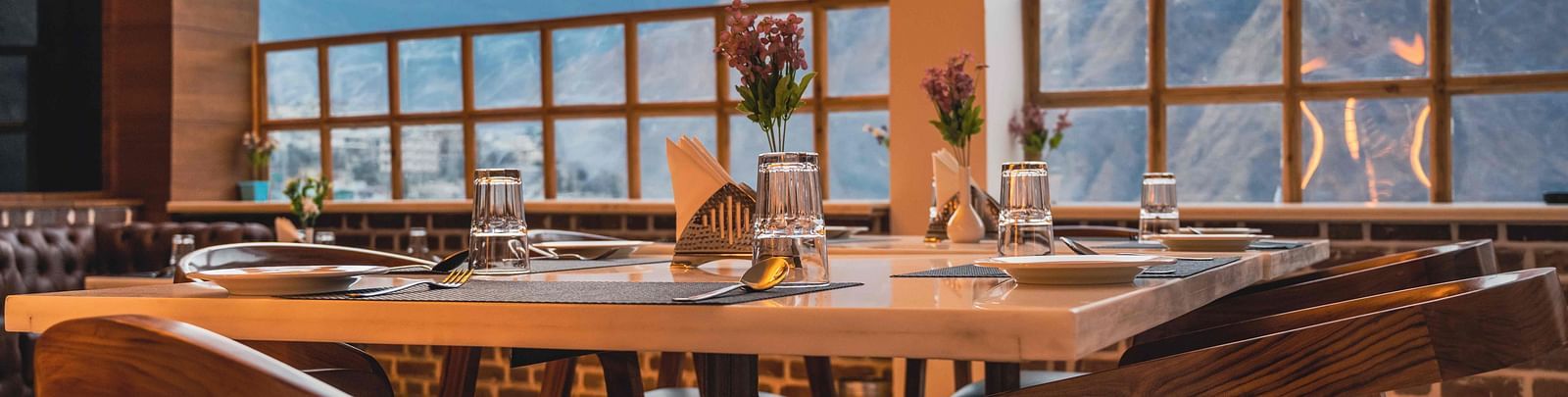 image of the indoor dining area of the alpenrose restaurant featuring a table over looking the beautiful mountain views - the tattva boutique resort