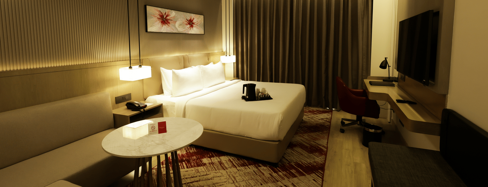Modern room with work desk, sofa seating, and ambient lighting at Ramada by Wyndham Sonipat Murthal