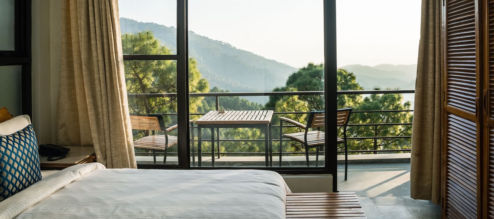 A bedroom with a balcony offering natural light and scenic views at BluSalzz Escapade Resort, Lansdowne