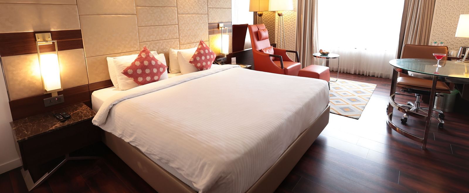 A spacious room with a large bed, a bedside table with a lamp, and curtains pulled to the side of the windows | Cenneys Gateway