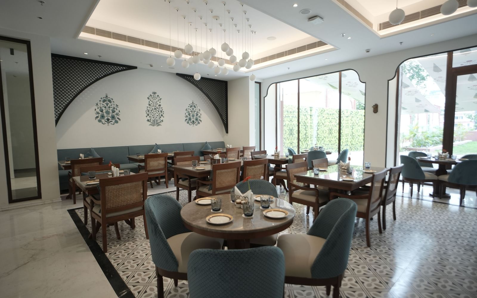 A brightly lit dining area with ample of natural lighting coming from the huge windows in the corner at Bhagirathi by RDB Atishay.