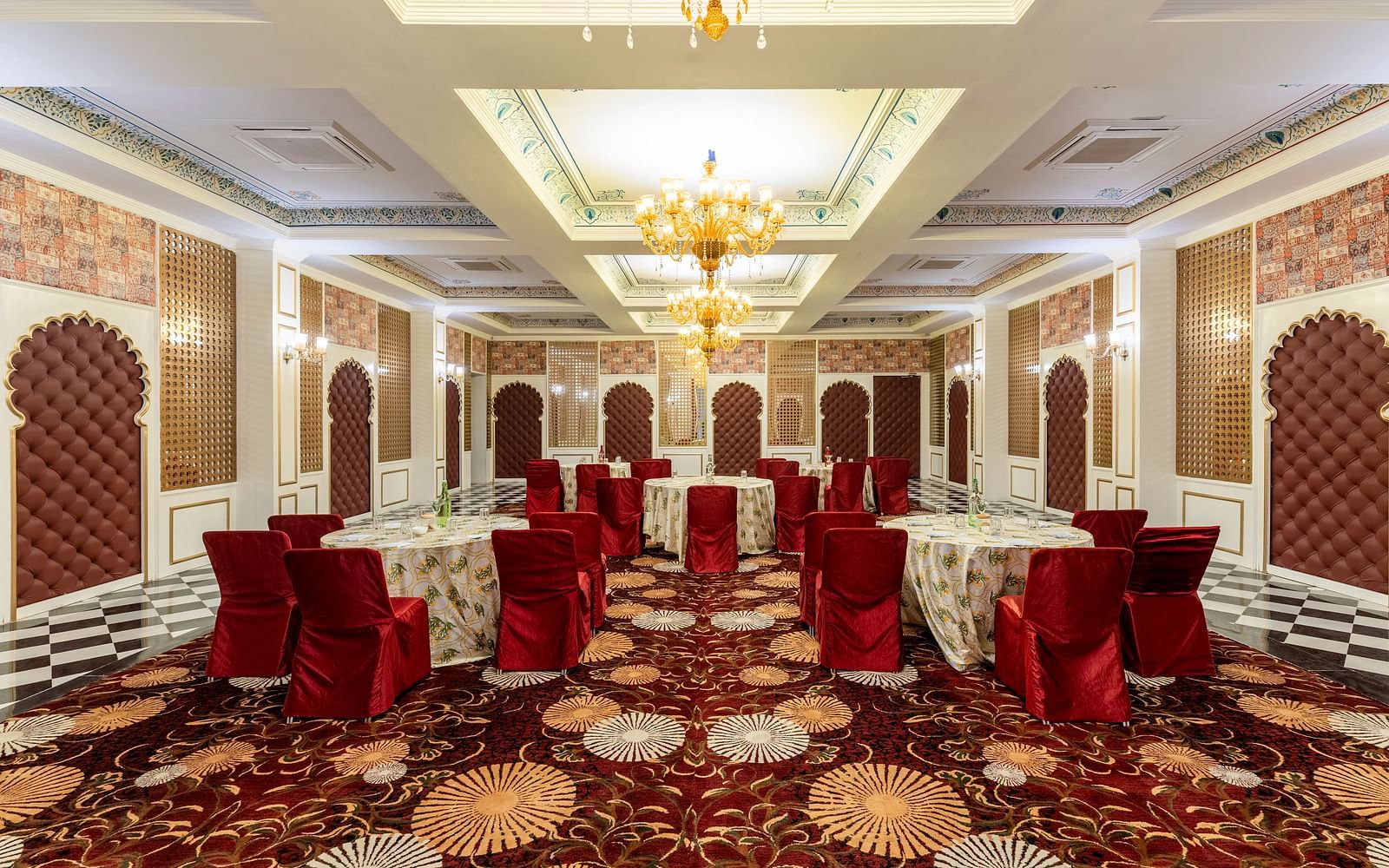 Luxurious banquet hall with red chairs and ornate ceiling at Kesar Bagh Palace.