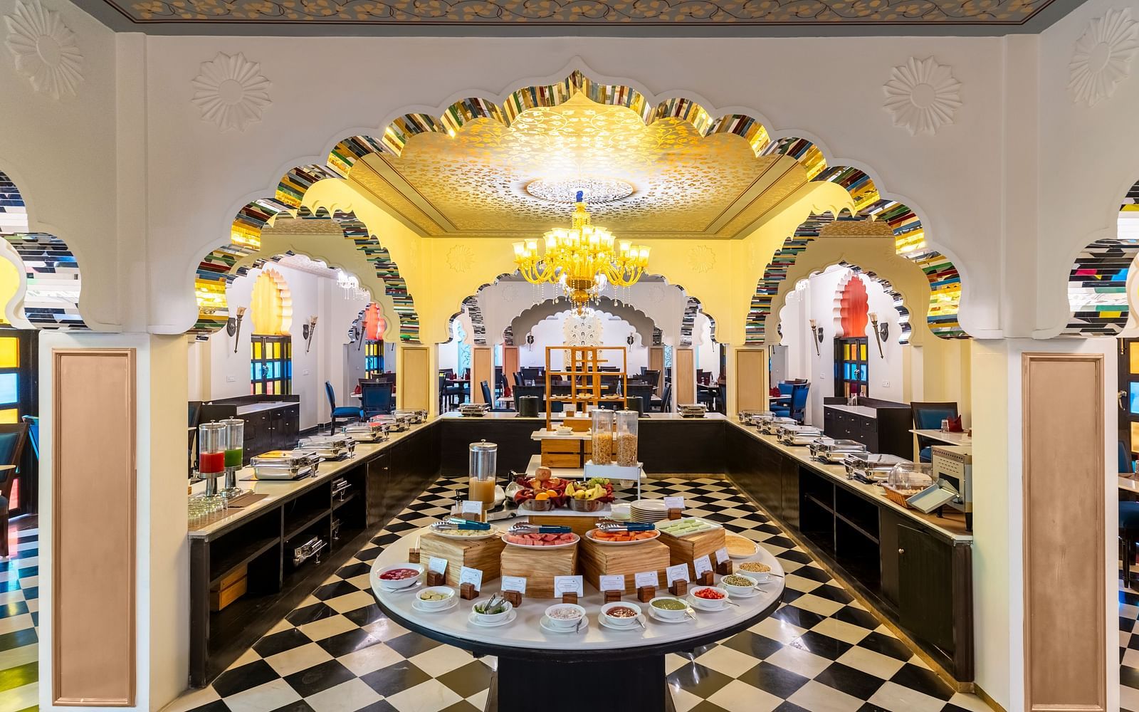 Lavish buffet dining area with black-and-white flooring and chandeliers at Kesar Bagh Palace.