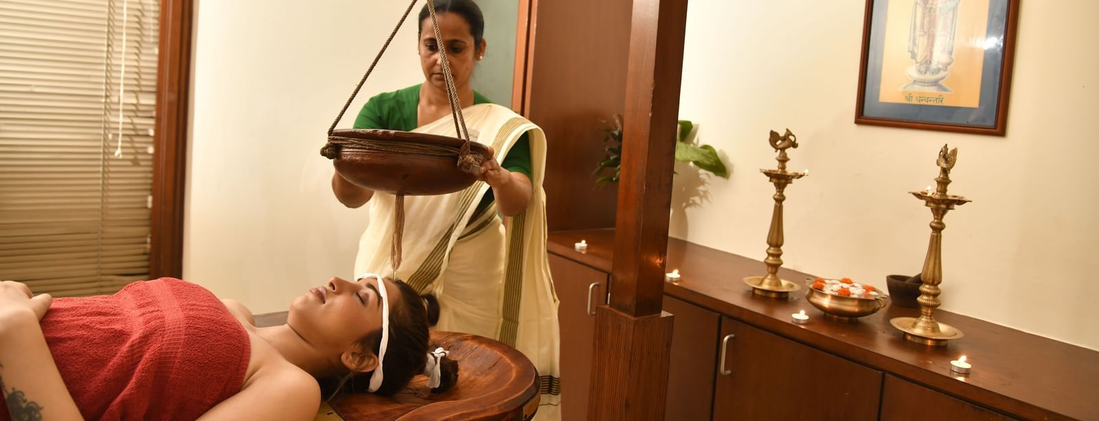 Woman receiving Shirodhara therapy as warm oil is gently poured on her forehead in a traditional Ayurvedic spa setting.