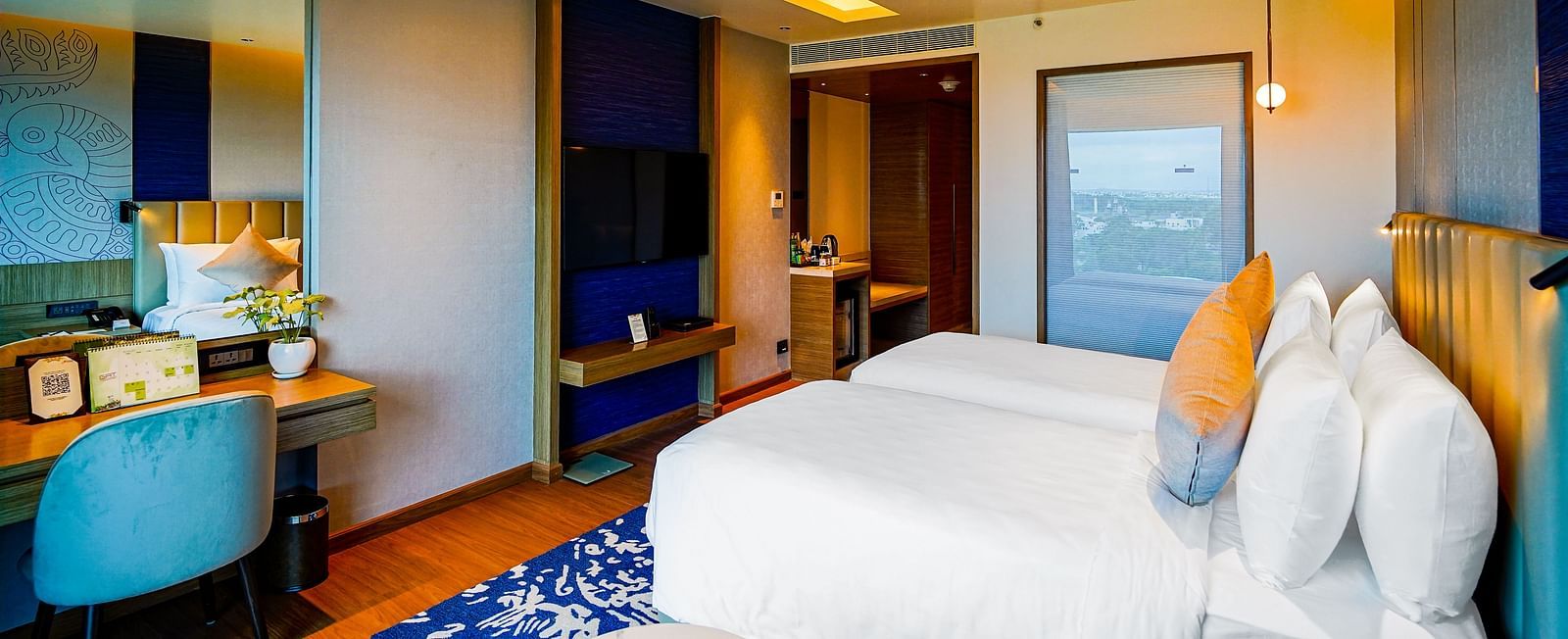 An image of Grand Club Temple View Room in Madurai with a twin bed, a work desk and hanging ceiling lamps