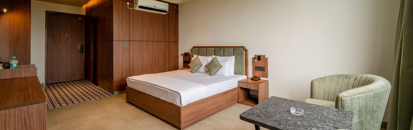 Elegant room with a large bed, armchairs, warm lighting, and a ceiling fan at Hotel Highway King, Neemrana.
