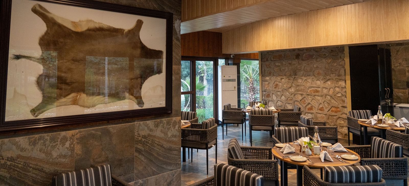 A spacious dining area at Aamaghati Jungle Retreat Ranthambore with stone walls and unique animal hide decor.