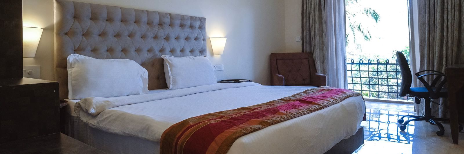 Spacious bedroom with a red runner on the bed, natural lighting, and balcony access at The Verda de Miranda Resort.