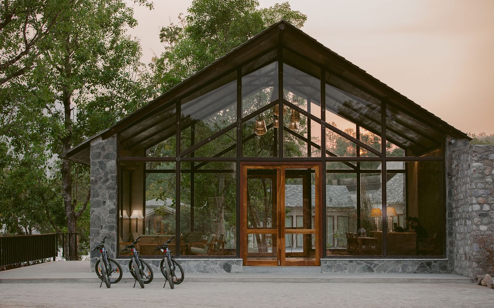 Entrance to Saraca Resort & Spa Corbett with large glass panels and wooden beams