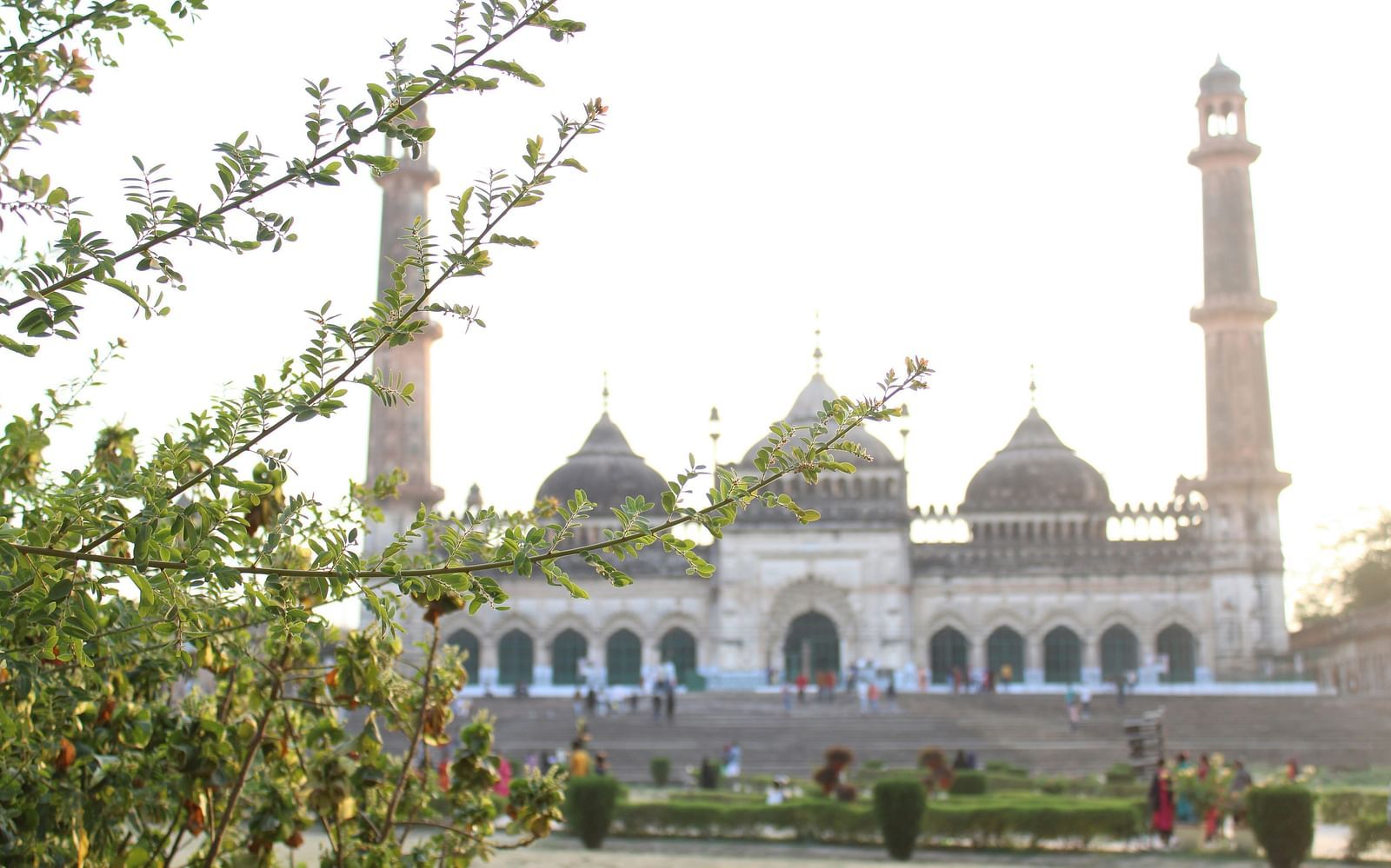 A far out view of Bara Imambara in Lucknow with people walking in front of it.