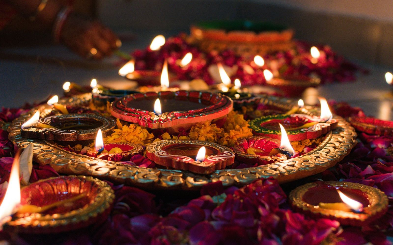 A close up shot of many lit diyas kept on a copper plate during diwali celebration