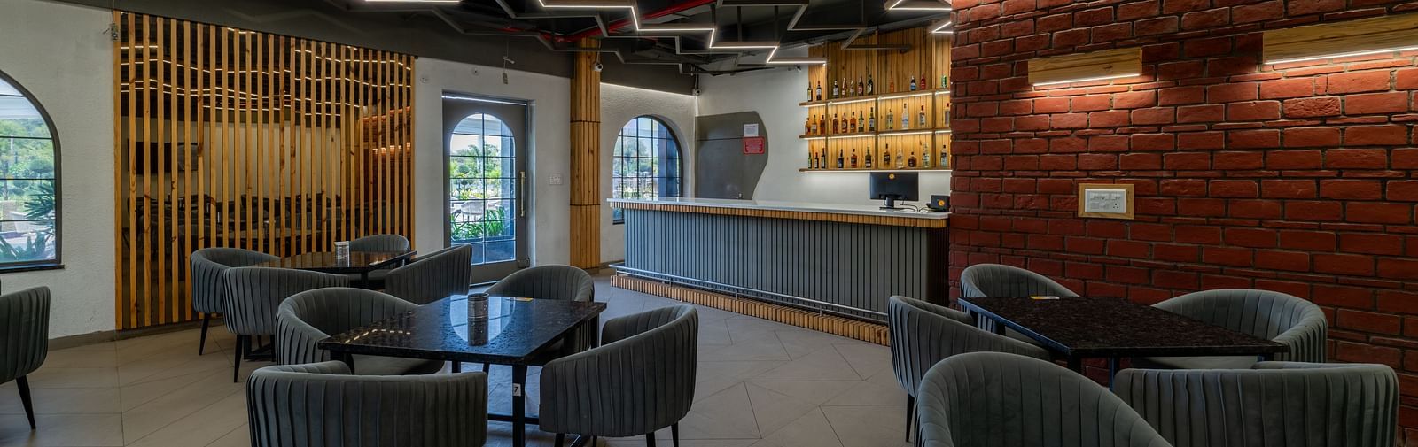 A lounge and bar space at Hotel Highway King, Bagru, featuring modern chairs, ambient lighting, and brick wall accents.
