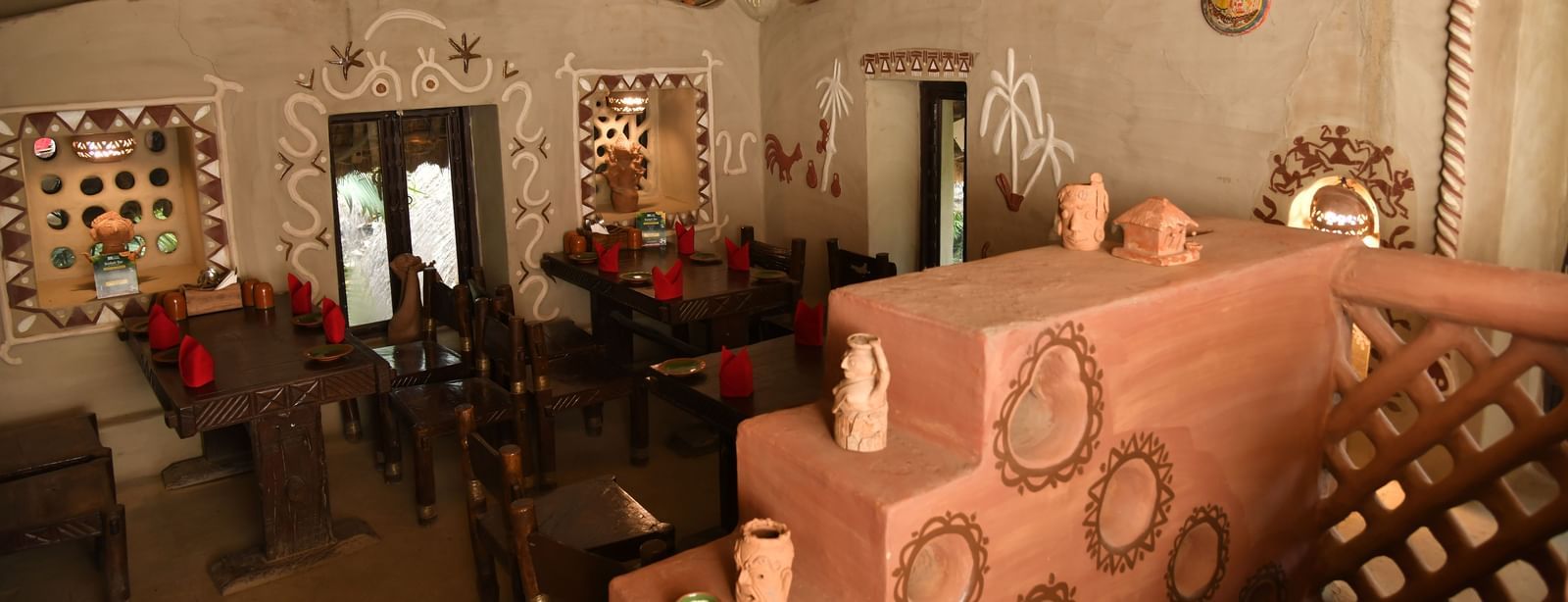 The interior of a restaurant with traditional decor, featuring a unique, textured wall and a clay oven or fireplace | Bhoomi Restaurant