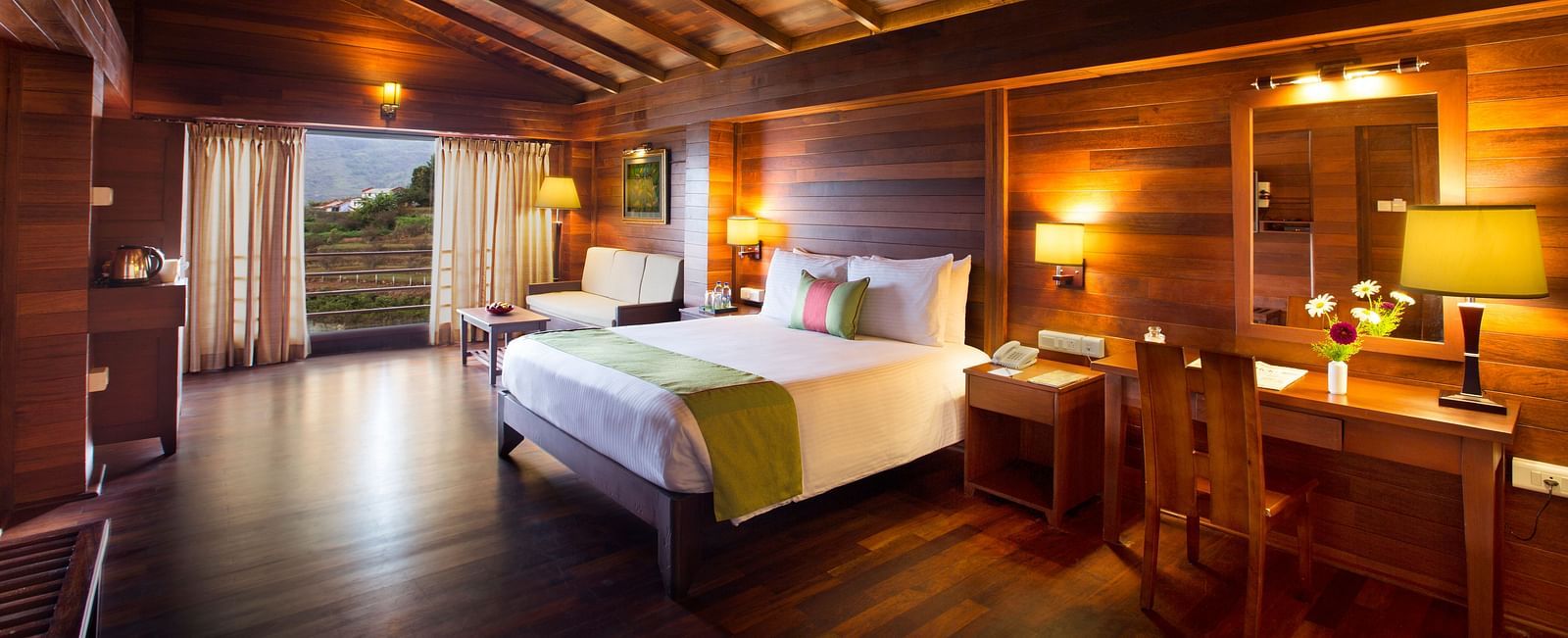 An image of Timber Charlet room with a king size bed, bed side table, lamps, a dressing table, chair, and other decorative items - GReaT Trails Kodaikanal By GRT Hotels