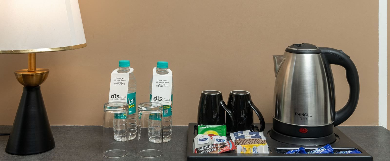 A close up shot of an electric kettle, two coffee mugs, two bottled water, and a lamp - DLS Ganga Bliss, Haridwar