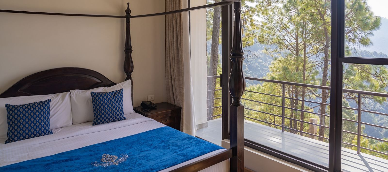 A bed with antique wooden pillars and a balcony next to it at BluSalzz Escapade Resort, Lansdowne
