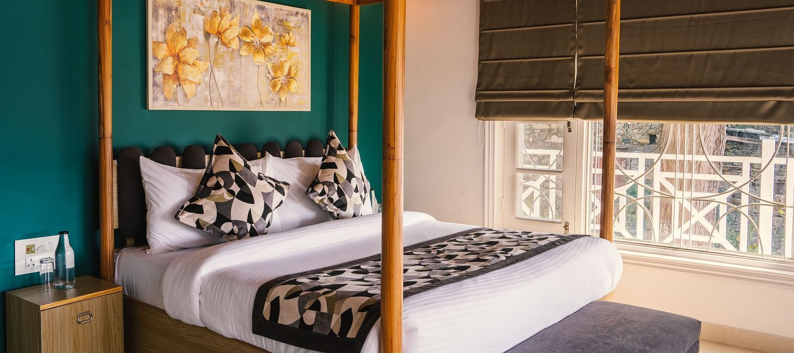 A spacious bed with a wooden frame, a photo frame above the headboard, and a half-closed window to the side at BluSalzz Villas - The Green Roof, Bhimtal.