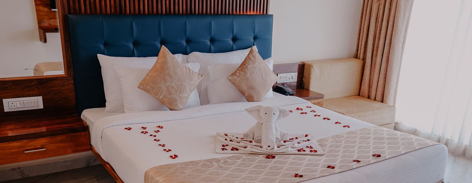 An image of a suite room featuring a bed, bed side tables, and a couch - Nisarga Lake Resort