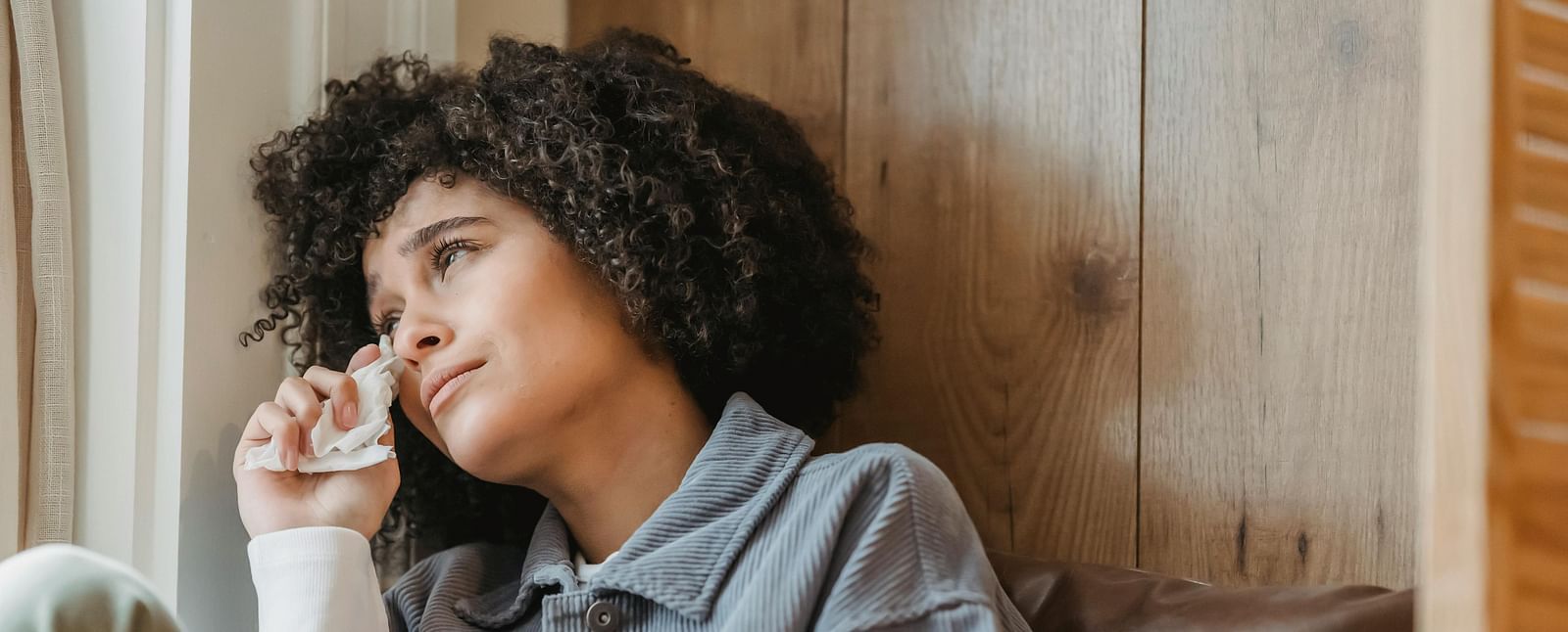 A woman leaning against a leather pillow, lost in a moment of reflection