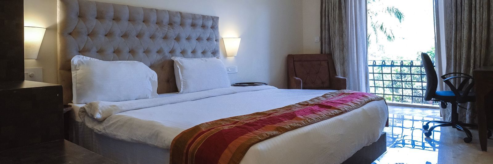Spacious bedroom with a red runner on the bed, natural lighting, and balcony access at The Verda de Miranda Resort.