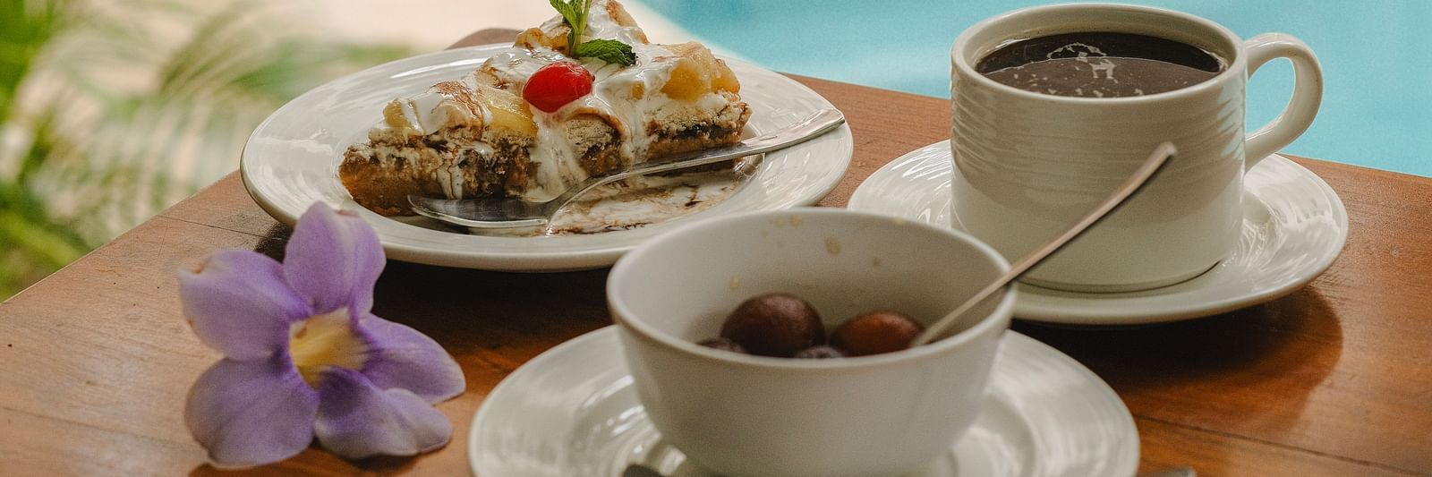 Breakfast spread with coffee, juice, and dessert beside a swimming pool at The Verda de Miranda Resort.