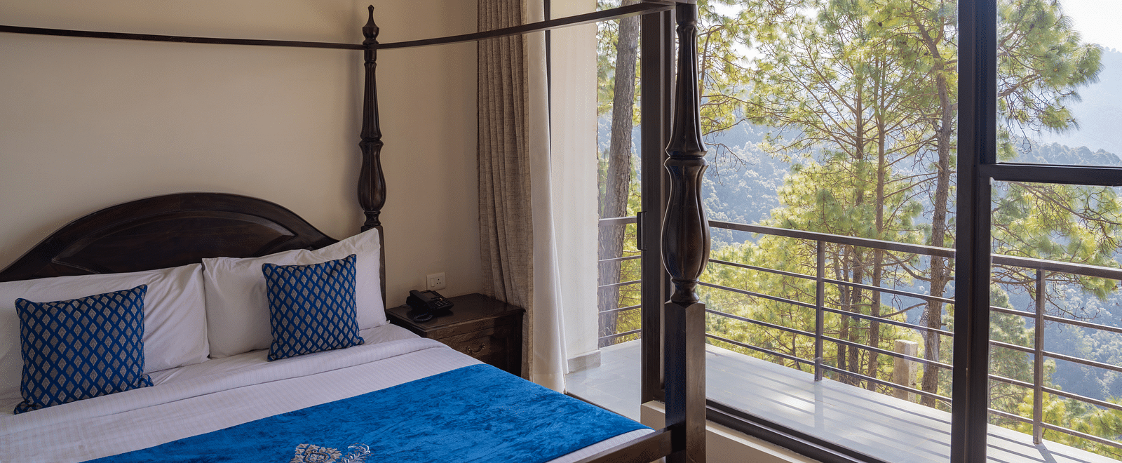 A bed with antique wooden pillars and a balcony next to it at BluSalzz Escapade Resort, Lansdowne