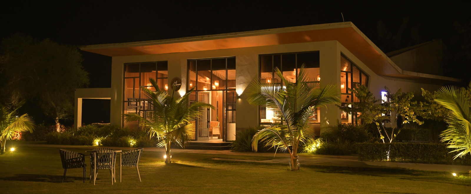 Restaurant building illuminated at night with warm lighting and garden views at Hotel Sonar Bangla Mayapur.
