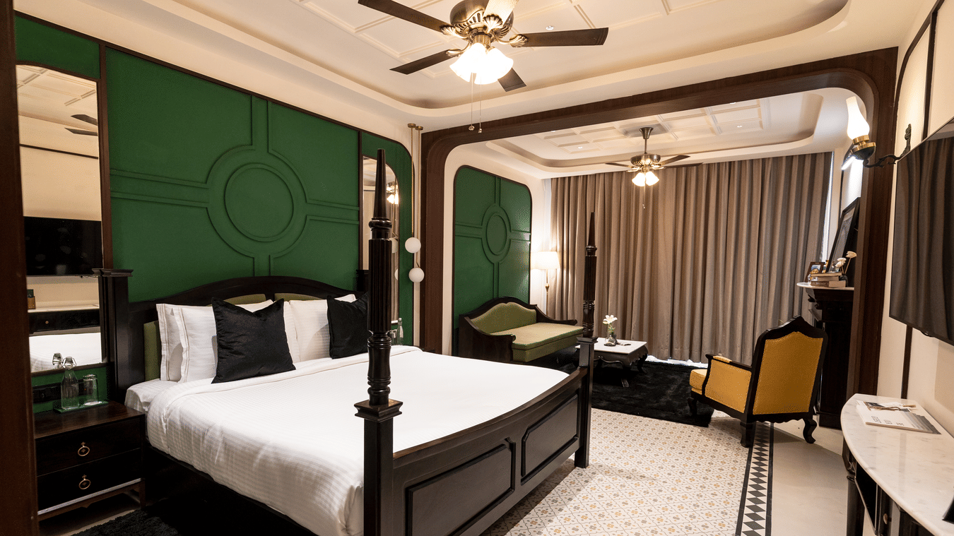An image of a bedroom with king size bed, flat TV screen, chair, and sofa - Polo Cherrapunjee Resort