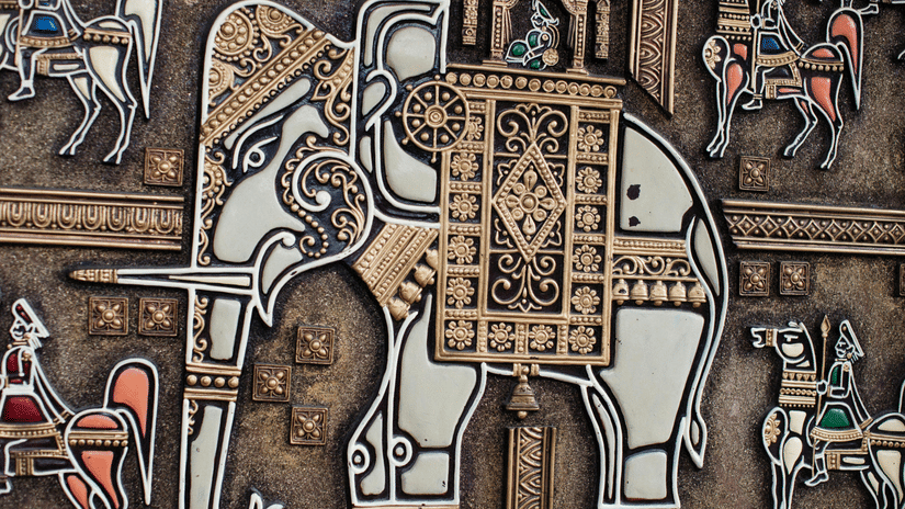 A decorative wall relief depicts a large, ornate elephant surrounded by smaller stylised horses and figures in a traditional art style.