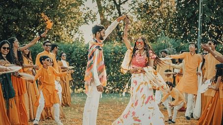 A woman and man dancing in traditional wear, surrounded by many people.