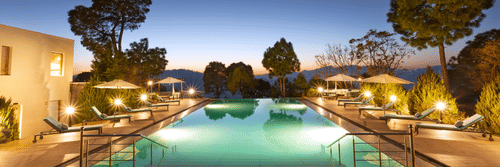 Image of a large swimming pool at Suryavilas in the evening as the premises are surrounded by trees