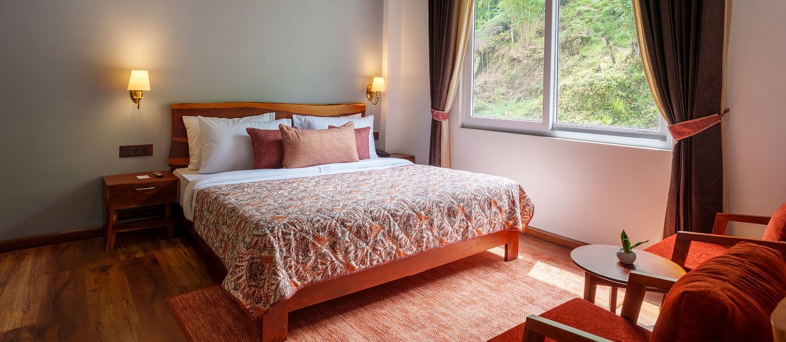  A hotel bedroom with a large bed, wooden ceiling, and a window providing natural light and a view of greenery, common in rooms at Summit Enigma Resort and Spa.