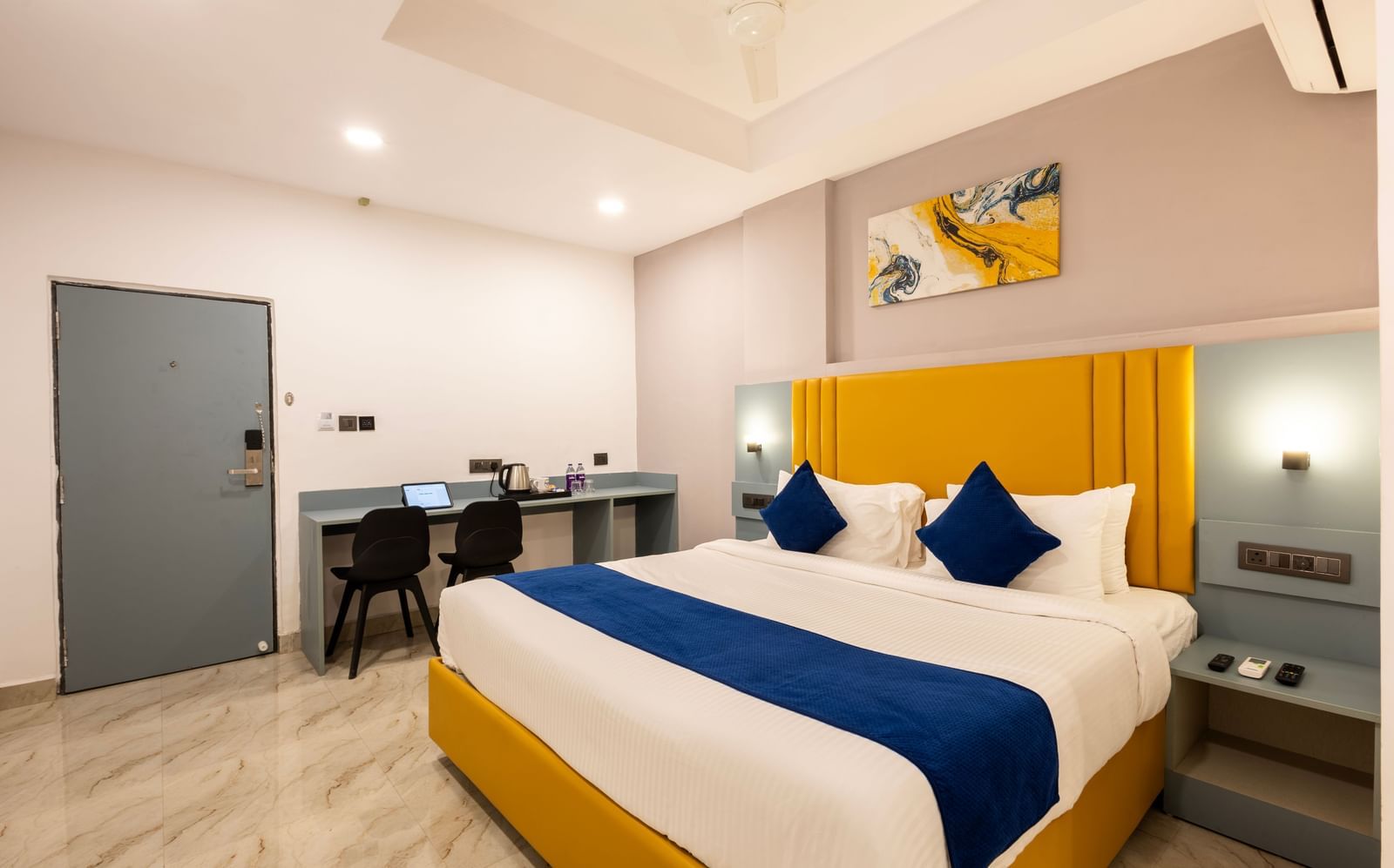 Overview of a modern Premium Room with a bed featuring blue accents, a work desk area, and a door on the left  - Beestay Hotels Financial District, Hyderabad 