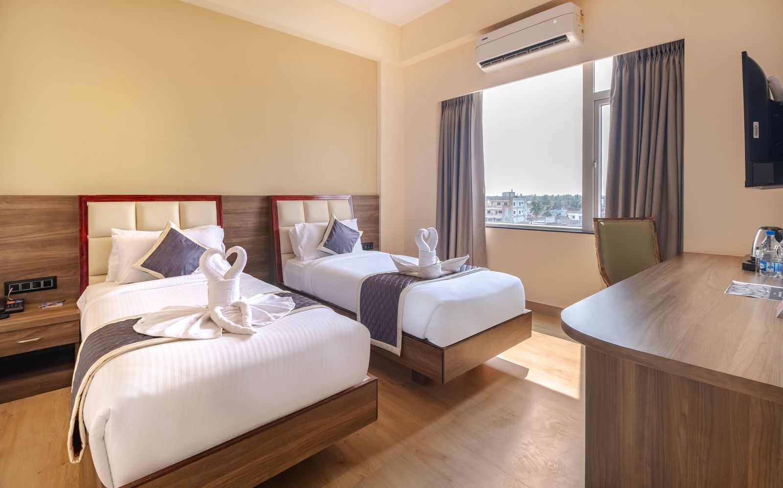 Spacious room at Monday Hotels Amalapuram Heights with warm tones, twin bed, air-conditioning, and window view.