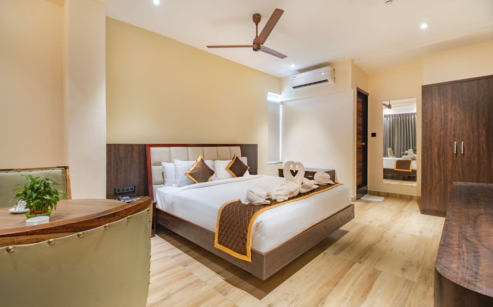 Spacious room at Monday Hotels Amalapuram Heights with double bed, ceiling fan, mirror, and air-conditioning.