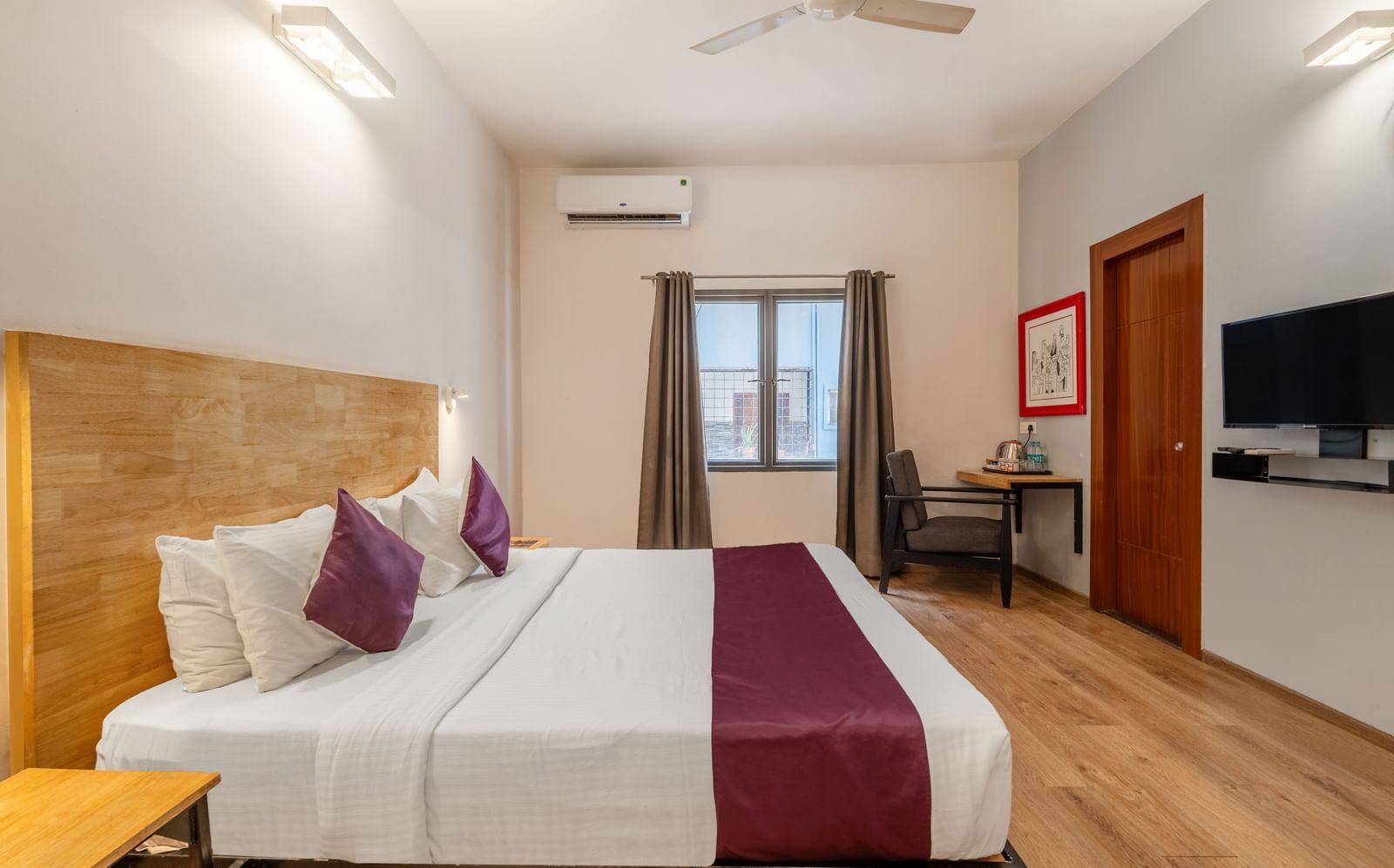 A hotel room with a double bed, a wall-mounted TV, and a window with the curtains opened - Monday Hotels HITEC City, Hyderabad