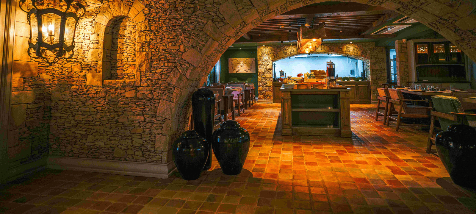 A dimly-lit entrace to the Mila restaurant at The Evren, Vagator, featuring a arched wall made of stone.