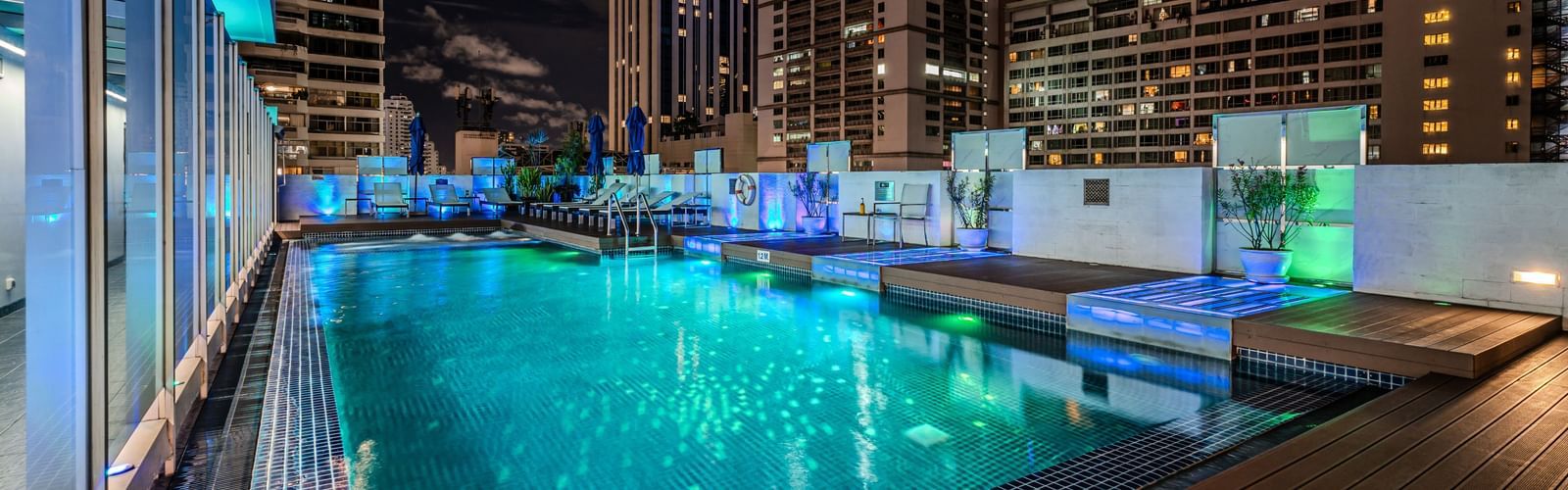 An overview of the rooftop swimming pool with the lights on  - Night Hotel Bangkok.