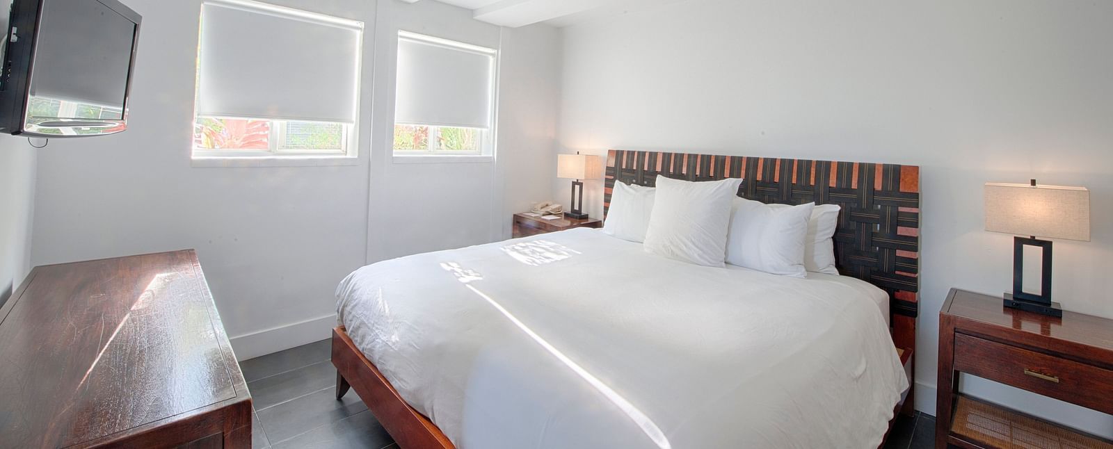 Bedroom at Casa Morada featuring a white bed, wooden furniture, and a wall-mounted TV.
