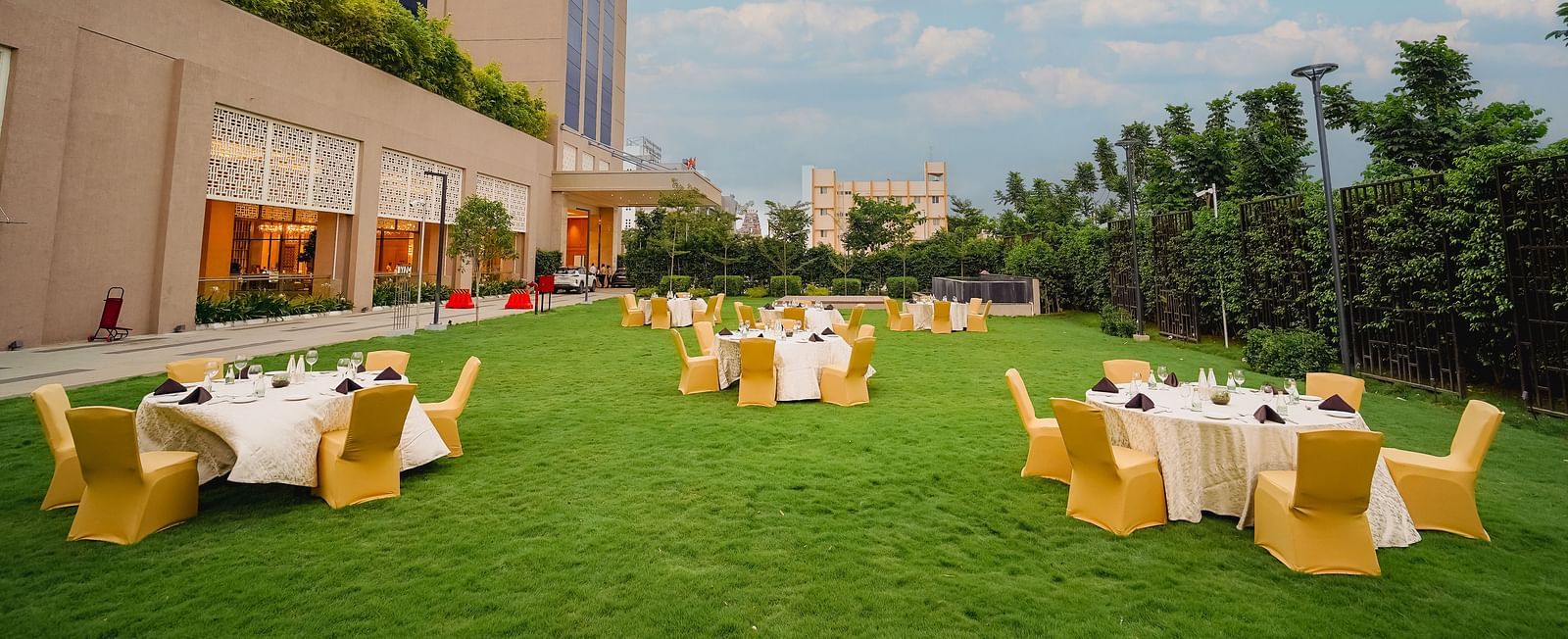 A beautifully manicured lawn with outdoor seating, perfect for events, surrounded by a hotel building