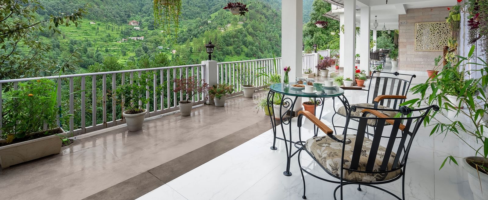 Open-air veranda with seating and potted plants overlooking forested hills, at BluSalzz Collection - Suvaasa Resort, Ramgarh.