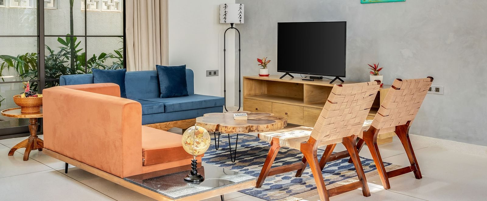 A vibrant living area with a blue sofa, orange armchair, a wooden coffee table, and artistic green wall decor - BluSalzz Villas - Alocassia, Anjuna